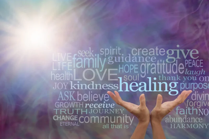 female hands reaching up to the word HEALING surrounded by a relevant word cloud with a sun burst and wispy multi coloured energy field background